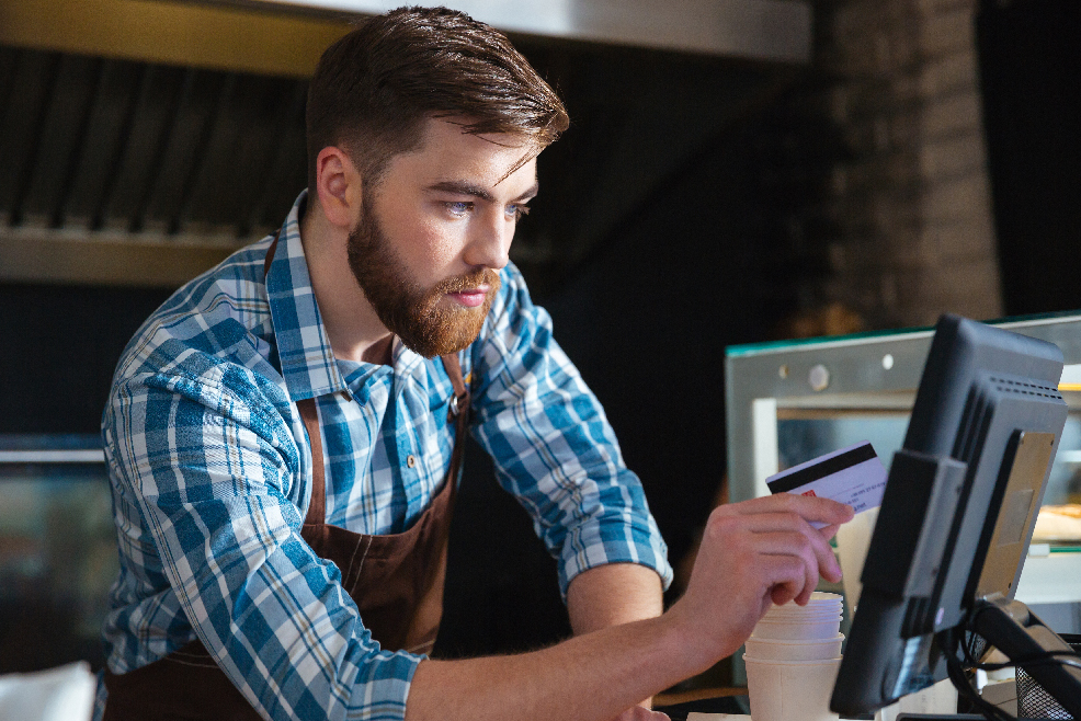 A small business owner processing credit card payment via touch screen POS on top of the counter table | CloudBanking